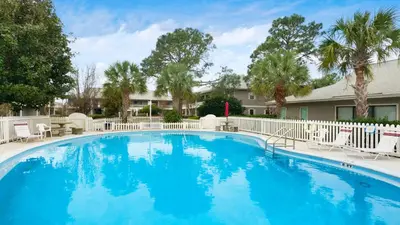 a large blue swimming pool with chairs and trees at Beachwood Villas 11E - SE Seagrove in Santa Rosa Beach