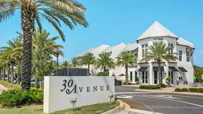 a sign in front of a building with palm trees at Sand Cliffs 107 in Seacrest
