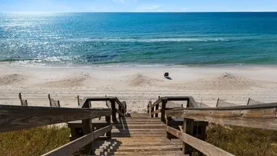 a wooden staircase leading to a beach with the ocean at Sand Cliffs 117 in Seacrest