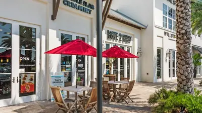 two tables with red umbrellas in front of a store at Sand Cliffs 117 in Seacrest