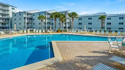 a swimming pool with chairs and a building at Sand Cliffs 415 in Seacrest