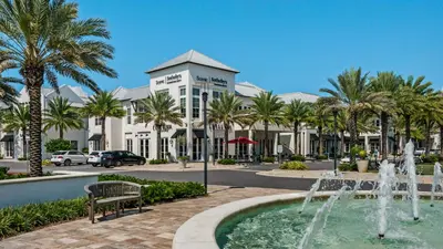 a fountain in front of a building with palm trees at Our Blue Haven in Inlet Beach