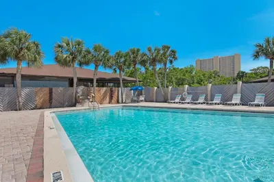 a large swimming pool with palm trees and chairs at Portside K5 in Panama City Beach