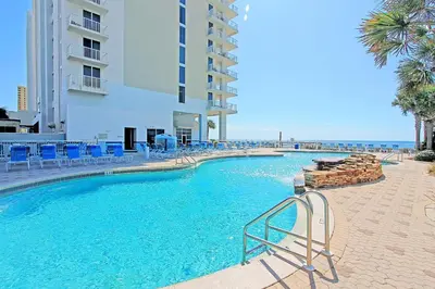 a swimming pool with blue chairs and a building at Majestic Beach Towers 1-1804 in Panama City Beach