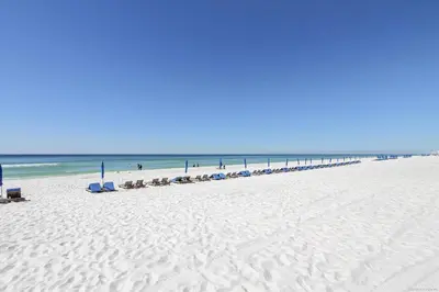 a beach with a line of beach chairs and the ocean at Shores of Panama 621-Sleeps 8, Free Beach Fun! Reserved Parking Space! condo in Panama City Beach