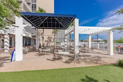 a patio with tables and chairs in a building at Stunning Ocean Views! Resort Beach Condo! Sleeps 8! by Dolce Vita Getaways PCB in Panama City Beach
