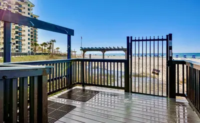 a wooden deck with a gate and the beach at Sunbird Resort! Direct Beachfront Condo! Free Beach Chairs! by Dolce Vita Getaways PCB in Panama City Beach