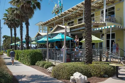a restaurant with people sitting under umbrellas outside of a building at Brand NEW Expansive Coastal Home w/ Custom Furnishings Sleeps 15 in Panama City Beach