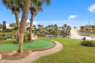 a golf course in a park with palm trees and a fountain at Large Balcony! Gulf Front Master Suite! Many Amenities On-Site! in Panama City Beach