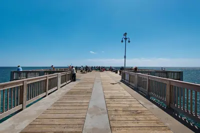 a pier with people walking on it next to the water at Charming Retreat, a Short Walk to Laguna Beach, with Room for 10! in Panama City Beach