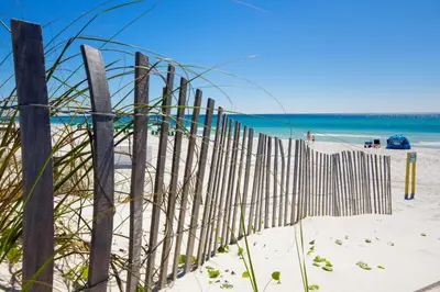 a fence on the beach with the ocean in the background at 120 Palm Beach Dr A - La Casa Turquesa in Panama City Beach