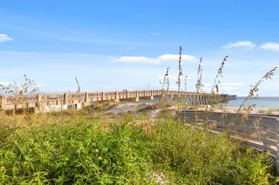a bridge over a beach next to the ocean at NEW PROPERTY! Vacation Right on the Gulf in Sand & Seafoam Villa Sleeps 6! in Panama City Beach