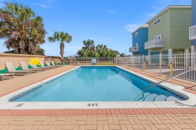 a swimming pool with chairs and a building at Next To Pier Park! STEPS from the Beach! Dog-Friendly! Pool! in Panama City Beach