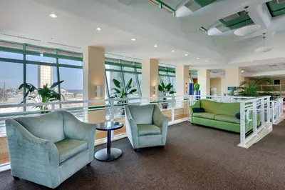 a lobby with two chairs and a table and windows at Emerald Beach Resort Condo-Gulf Front+Beach Access! Beach Chair Service! in Panama City Beach