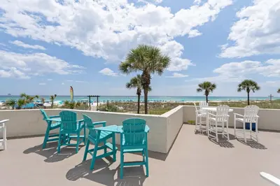 a patio with chairs and tables and the beach at Top Of The Gulf 704 in Panama City Beach