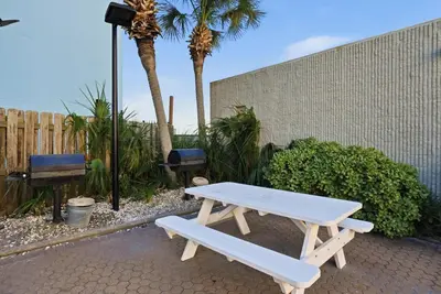 a white picnic table sitting next to a fence at Top Of The Gulf 704 in Panama City Beach