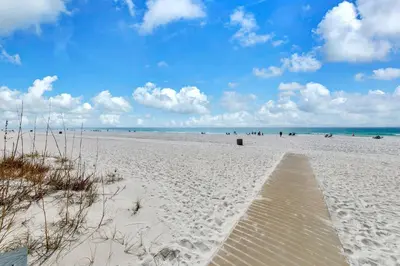 a sandy beach with a wooden pathway to the ocean at Sunbird 709W Beach Life in Panama City Beach