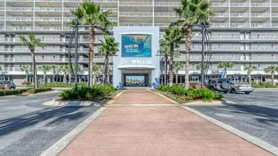 a walkway in front of a building with palm trees at Keep It Beachy at Laketown Wharf #611 by Nautical Properties Vacation Rentals in Panama City Beach