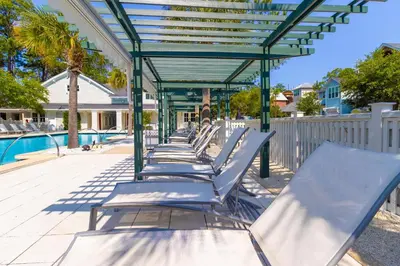 a row of chaise lounges next to a pool at Anchored on 30A in Santa Rosa Beach